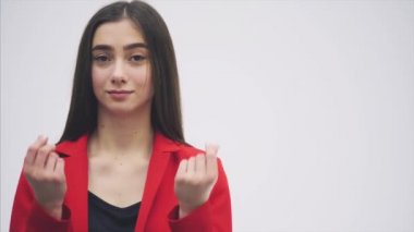 Güzel bir genç esmer portresi. Kameraya bak. Bu sırasında elini kaldırdı ve bir jest para göstermeye başladı. Kırmızı bir ceket giymiş.