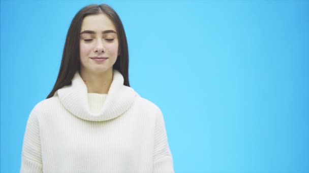 Junges hübsches Mädchen in weißen Kleidern. Während dieser Zeit steht es auf blauem Hintergrund. hält ein Wort der Liebe in Händen. — Stockvideo