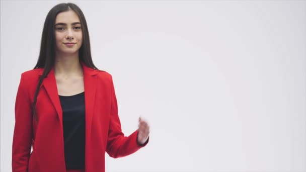 Retrato de una hermosa joven morena. Mira la cámara. Durante esto levantó las manos, señalando una clase de gestos. Vestido con una chaqueta roja . — Vídeos de Stock