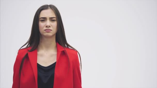 Retrato de una hermosa joven morena. Mira a la cámara. Durante esto levantó las manos, mostrando un gesto de placer vestida con una chaqueta roja . — Vídeo de stock