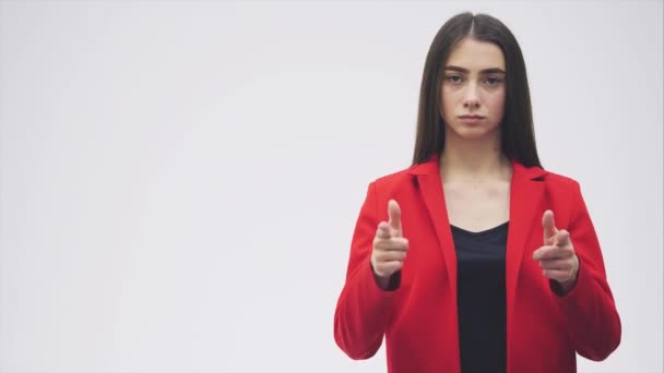 Jonge mooie brunette vrouw. Gekleed in een rode jas. Toont een symbolisch gebaar van een pistool, een gebaar van het spel. — Stockvideo