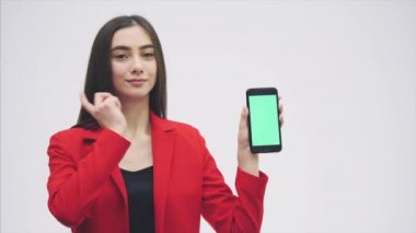Genç kırmızı bir ceket giyen kız tatlı çocuk. Gri bir arka plan üzerinde kalır. Bu süre boyunca, siyah bir telefon tutar. Yeşil ekran. Yavaş video.