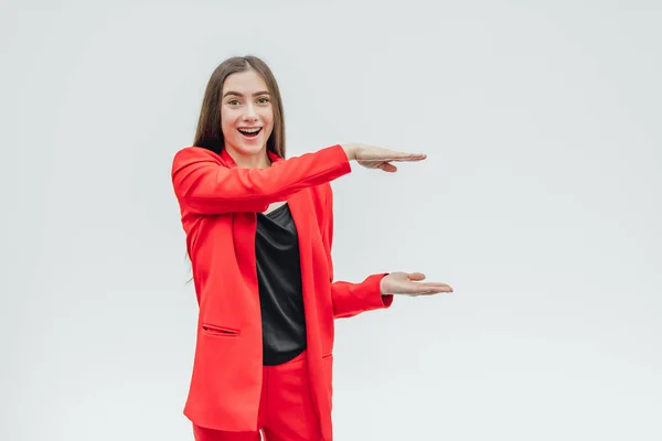 Retrato de uma bela jovem morena. Durante isso, a menina levantou as duas mãos. A mostrar o avião com as mãos. Vestido com uma jaqueta vermelha . — Fotografia de Stock