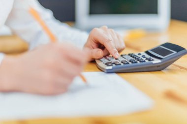 Raporun finansal verileri hesaplamak için Hesap makinesinde çalışan bir kalem tutan bir kalem tutan bir işadamı kapalı.