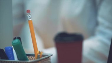 Kalem kalem işaretleri masaya yakın çekim. Bu bulanık genç iş kadını inşaat sırasında bir laptop için. Bir süre sonra bu iş yerine koymak için bir kalem alır.