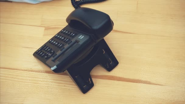 Jovem empresária segurando um telefone conjunto de mão e pressione o botão para fazer uma chamada. Perto está um caderno preto fechado . — Vídeo de Stock