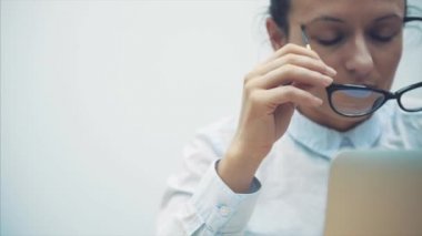 Bir güzel, çekici, şık, Zeki öğretmen modern bir saç modeli ile portresi. Bir dizüstü bilgisayarda çalışırken, metin mesajları gözatar. WiFi Internet kullanarak sohbet iletişim kurmak. Gözlük vuruyor