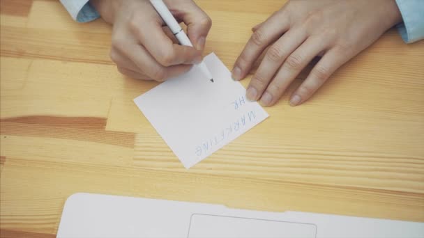 Eine weiße Geschäftsfrau beim Schreiben von Plänen für einen Geschäftstag. Blick nach oben. versehentlich neutralisiert das Blatt mit dem Schriftzug. Zeitlupe. — Stockvideo