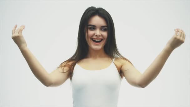 Glad ung söt flicka som står på en vit bakgrund. Klädd i en vit skjorta. Leka med hennes hår och vrida huvudet i olika riktningar — Stockvideo