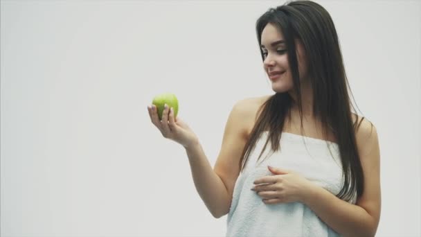 Portret van een aantrekkelijk meisje op een witte achtergrond. Uitvoeren en de behandeling van de groene appel. Geïsoleerd op een witte achtergrond. Gezonde manier van leven, voeding. — Stockvideo