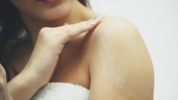 Detail krásná mladá dívka s Krémová pleťová voda, která se vztahuje k její rameno, cítí šťastný a veselý vlhkost její zdravé kůže, koncept péče o pleť. — Stock video