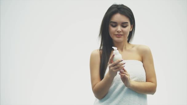 Крупним планом красива молода дівчина з вершковим лосьйоном, яка відноситься до її плеча, відчуває себе щасливою і веселою для вологи її здорової шкіри, концепції догляду за шкірою . — стокове відео