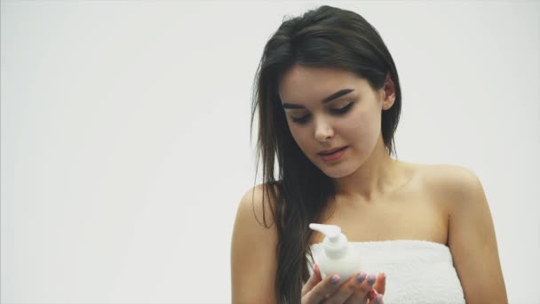 Close-up van een mooi jong meisje met romige lotion, die betrekking op haar schouder heeft, het gevoel van gelukkig en vrolijk zijn voor het vocht van haar gezonde huid, het concept van huidverzorging. — Stockvideo