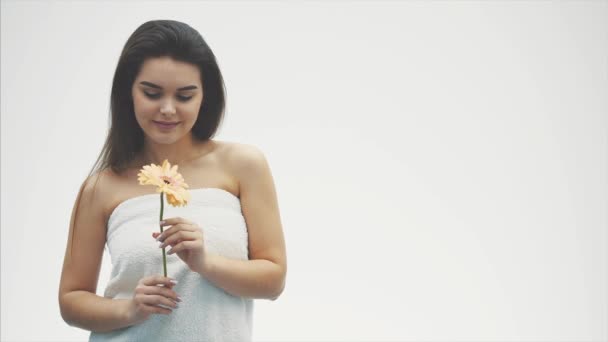 Jovem mulher bonita relaxando com flor de Gerbera no spa. Isolado sobre um fundo branco . — Vídeo de Stock