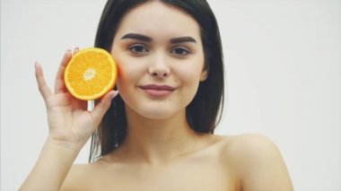 Güzel genç kız uzun saçlı deri ve mükemmel makyaj mükemmel. Turuncu meyve gözün arka plan üzerinde tutun. Beyaz arka plan.