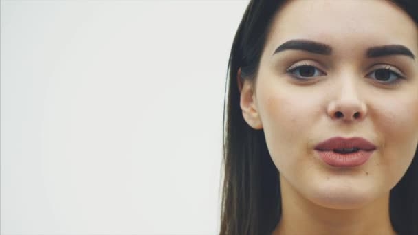 Skönheten i en kvinna med perfekt makeup gör en kyss gest. Närbild porträtt av en vacker söt charmig glad tjej, att ha en vacker kropp genom att skicka en air kyss. Isolerad på en vit — Stockvideo