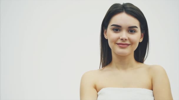 Mooie jonge meisje mannequin met een schijfje sinaasappel op een witte achtergrond. Met make-up en mooie zwarte lange haren. — Stockvideo