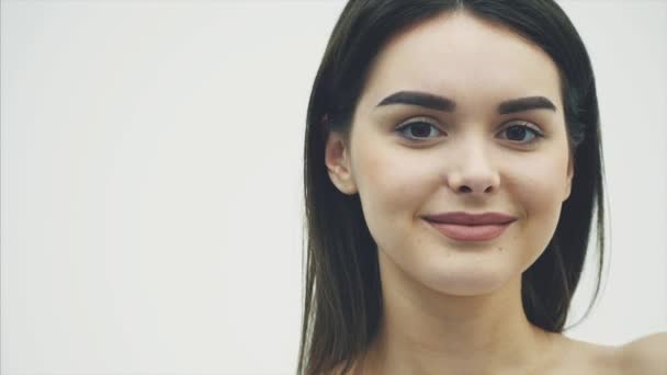 Närbild av en ung vacker flicka modell från en bit av orange på vit bakgrund. Med smink och vackra svarta långa hår. — Stockvideo