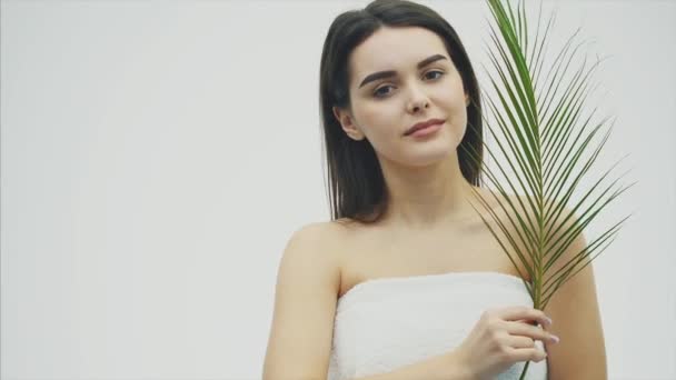 Joven modelo sonriente hermosa con maquillaje natural, pestañas largas y hoja verde de helechos. Spa, cuidado de la piel y bienestar . — Vídeos de Stock