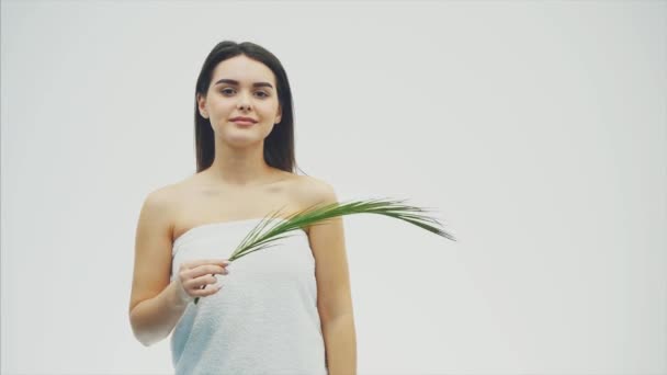 Jonge mooie lachende model met natuurlijke make-up, lange wimpers en groene blad van varens. Wellness, skincare en wellness. — Stockvideo