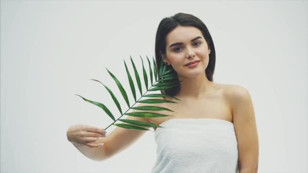 Beautiful young woman with perfect skin and natural make up posing front of plant tropical green leaves background with fern. Young model with wet hair care of her face and body. — Stock Video