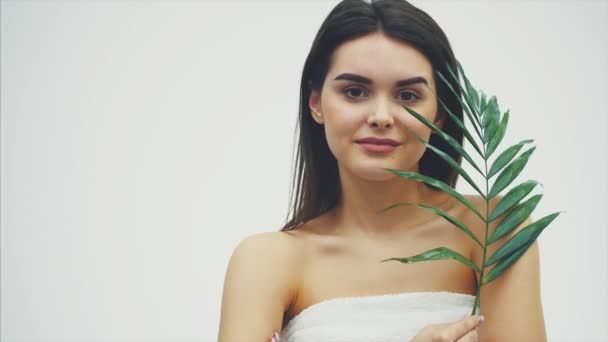 Mooie jonge vrouw met een perfecte huid en natuurlijke make-up poseren voorzijde van plant tropische groene bladeren achtergrond met fern. Jonge model met natte haren verzorging van haar gezicht en lichaam. — Stockvideo