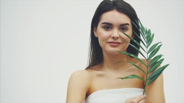 Mulher bonita com pele perfeita e natural compõem posando frente de planta verde tropical folhas de fundo com samambaia. Modelo jovem com cuidado de cabelo molhado de seu rosto e corpo . — Vídeo de Stock