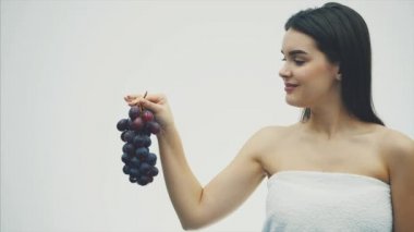 Güzel kız sağlıklı meyve yeme incedir. Olgun üzüm buket ve doğru tutan genç ve güzel bir kadın portresi.