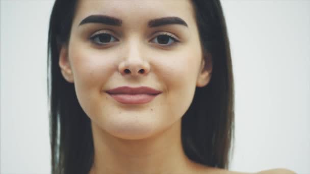 Ung vacker flicka som står på en vit bakgrund. Under denna hålls i nivå med ögat, kiwi partiklarna open-eyed, visar dem. — Stockvideo