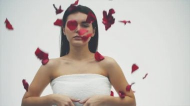 Güzel esmer kız onun güzelliğine. Bir altın akşam makyaj ve kırmızı ruj beyaz zemin üzerine koyu saçlı. kırmızı gül, yüzüne düşen düşen yaprakları.