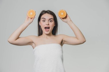 Mutlu genç kız meyve ile poz veriyor. Bu sırada elleri adet portakal ile büyüdü. Turuncu iki adet silah baş düzeyde tutar. Beyaz arka plan.