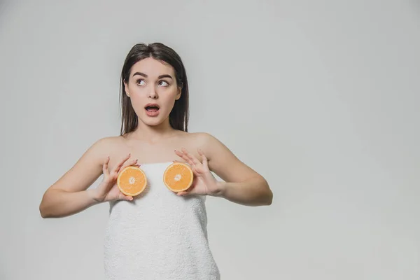 Glückliches junges Mädchen posiert mit Früchten. Fragmente einer Orange in den Händen auf weißem Hintergrund. Heben Sie die Arme auf die Höhe der Brust, werden zwei Fruchtstücke gehalten. — Stockfoto