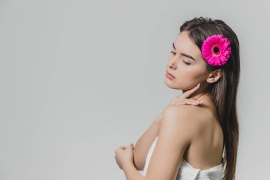 Genç güzel kız onun saç ayakta beyaz bir arka plan üzerinde bir çiçek. Güzel uzun siyah saçları var. Bu sırada bir yana görünüyor. Arkadan Görünüm.