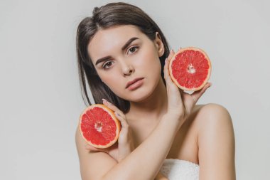 Neşeli bir kız greyfurt iki bölümden yüzünün tutar. O gülümsüyor ve ileri mutluluk için görünüyor. Arka plan üzerinde izole