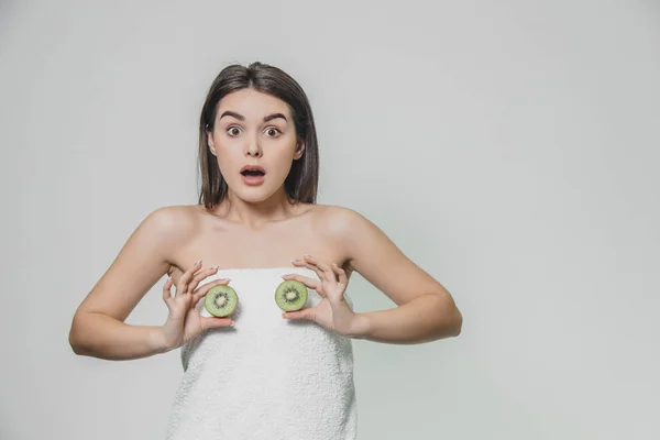 Joven chica bonita de pie sobre un fondo blanco. Durante este tiempo, a nivel del pecho, las partículas de kiwi se mantienen en las manos . —  Fotos de Stock