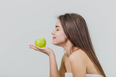 Çekici bir beyaz kız gülümseyerek portresi. Beyaz arka plan üzerinde izole kadın. Yeşil elma elinde tutar. İyi temiz cilt.