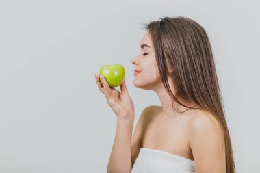 Çekici bir beyaz kız gülümseyerek portresi. Beyaz arka plan üzerinde izole kadın. Yeşil elma elinde tutar. İyi temiz cilt.