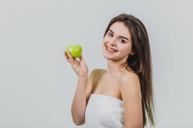 Çekici bir beyaz kız gülümseyerek portresi. Beyaz arka plan üzerinde izole kadın. Yeşil elma elinde tutar. İyi temiz cilt.