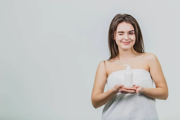 Vzhled modelu je krásné mladé dvojče v bílé Froté ručník. Použití tělové mléko na jejím rameni a usmívá se přitom stát na bílém pozadí. — Stock fotografie