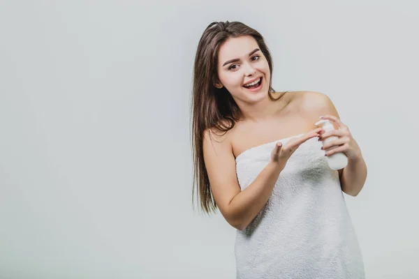 Vzhled modelu je krásné mladé dvojče v bílé Froté ručník. Použití tělové mléko na jejím rameni a usmívá se přitom stát na bílém pozadí. — Stock fotografie