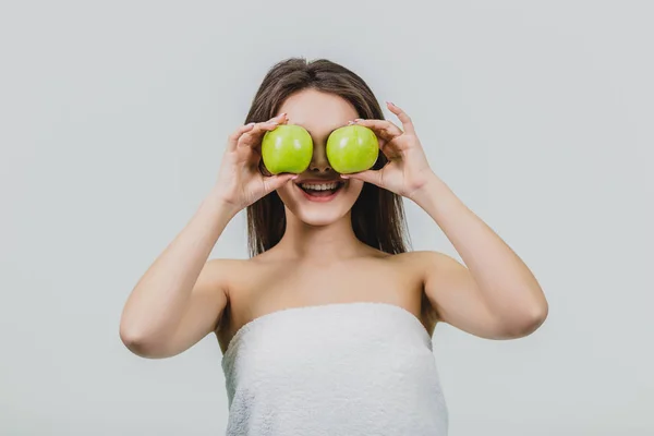 Divertida mujer riendo sosteniendo dos manzanas verdes en sus ojos. Fondo blanco de un concepto de alimentación saludable. Dieta — Foto de Stock