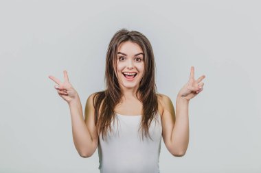 Beyaz bir arka plan üzerinde kız selamlıyor. Gölge atış büyüleyici bir genç kadın, iki elle, kaldırma v işaret gösteren kamera ve gülümsüyor, grev ya da baştan bırakmasına benziyor