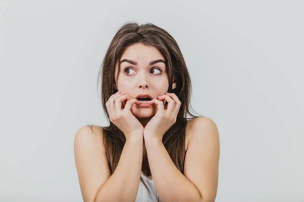 Giovane ragazza è piuttosto caucasico in piedi su uno sfondo bianco. Per questa volta vestito con una t-shirt bianca e jeans blu. Durante questo periodo, gli mise le mani sul viso con stupore. Ha bello — Foto Stock