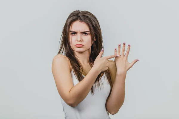 Young girl is pretty Caucasian standing in a white background. Shows the index finger to the finger of another hand. — Stock Photo, Image