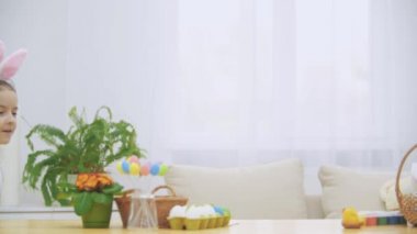 Neşeli oyun kız tavşan kulakları kafasında ile ahşap masa altında yavaş tarafından saklanıyor. Yavaş yavaş kendini gizleme aşağı dowing kızdır.