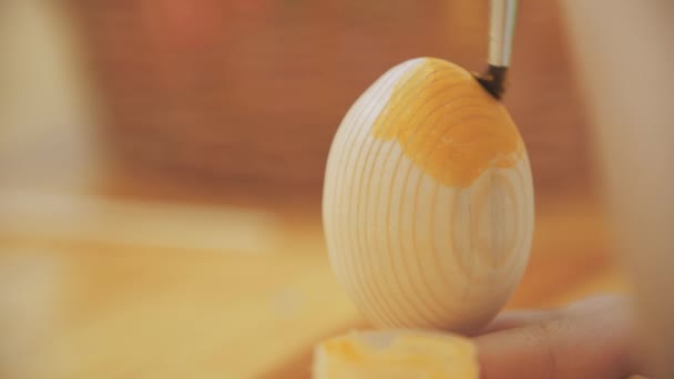 Ragazzo creativo sta dipingendo un uovo di Pasqua in un colore giallo con un aiuto di pennello . — Video Stock