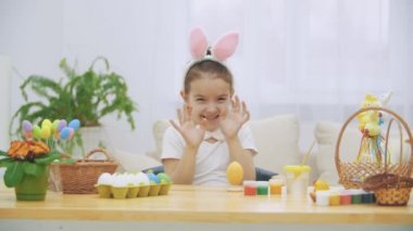 Küçük şirin ve sevimli kız, yüz güzellik lekeler ile içtenlikle gülümsüyor. Kız onun daire el gösterilen, sonra kabarık kravat fiyonk dokunmadan ve bu oldukça üzerinde onu soyunma yüz