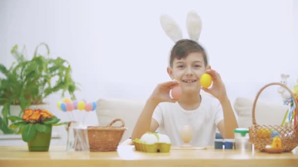 Leuk en schattig jongetje glimlachend en spelen met kleurrijke kippen eieren in zijn handen. Concept paasvakantie. — Stockvideo