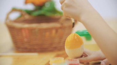 Neşeli çocuk boya fırçası yardımıyla bir sarı renkte bir Paskalya yortusu yumurta boyama.