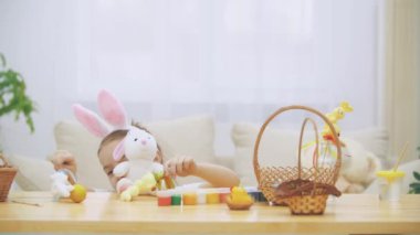 Küçük şirin ve sevimli kız gülümseyerek ve renkli tavuk yumurtaları ve bunnies ile oynuyor. Kavram Paskalya tatili.